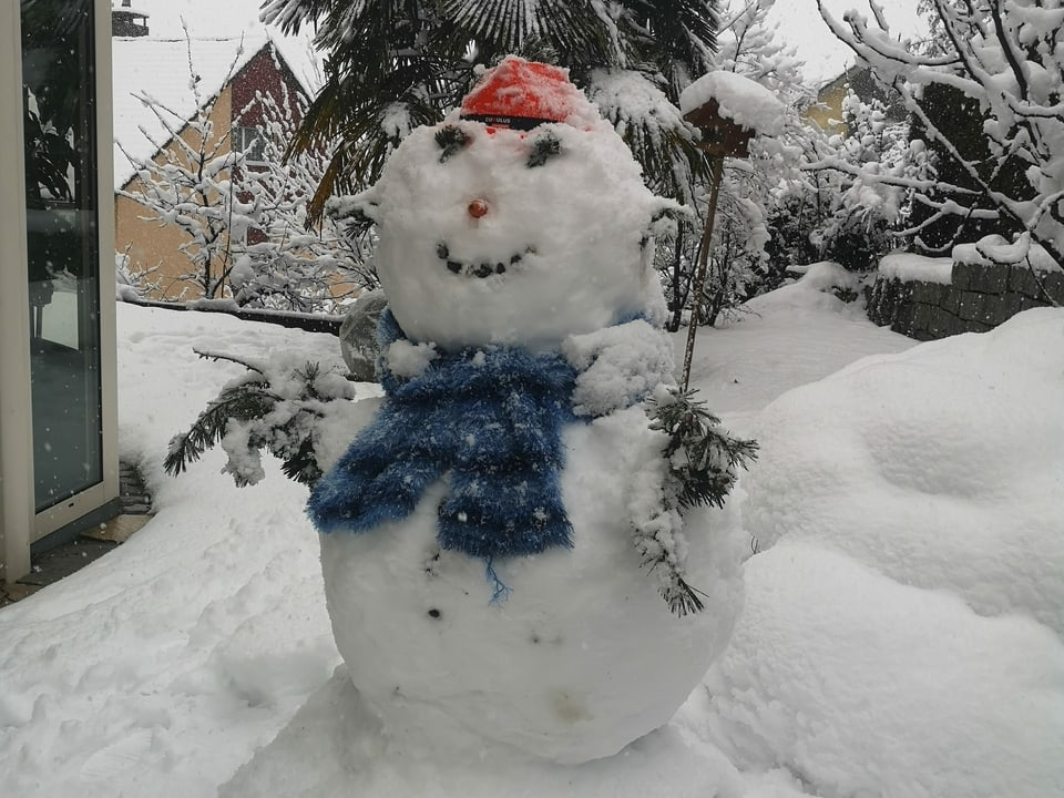 Schneemann in einem verschneiten Garten.
