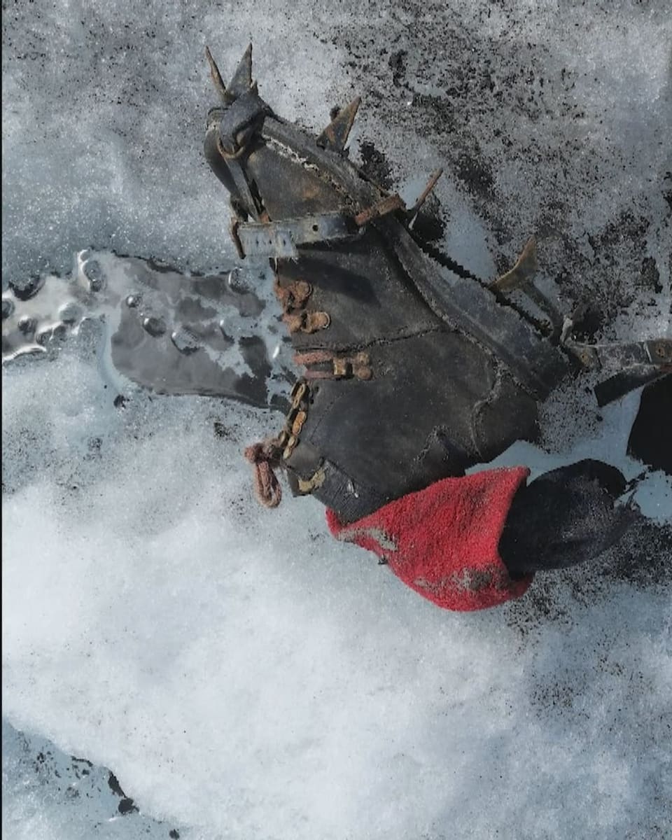 Ein alter Schuh mit Steigeisen liegt auf dem Gletschereis. Aus dem Schaft ragt ein Socken.