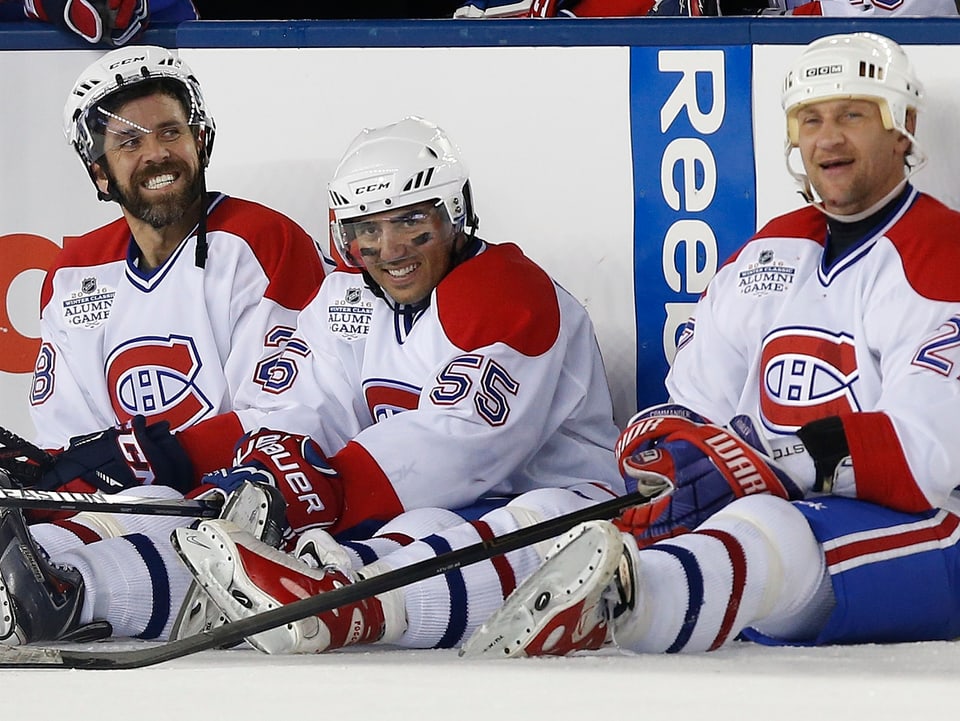 Eric Desjardins, Francis Bouillon und Alexej Kowalew sitzen lachend auf dem Eis.