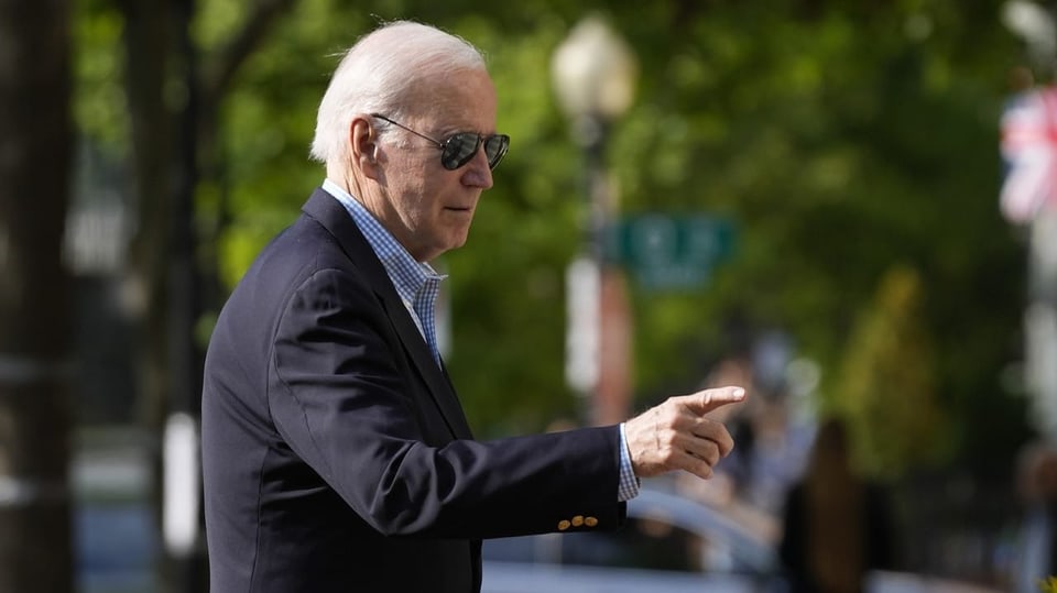 US-Präsident Joe Biden trägt eine Sonnenbrille und einen Anzug und hat seinen rechten Zeigefinger ausgestreckt.