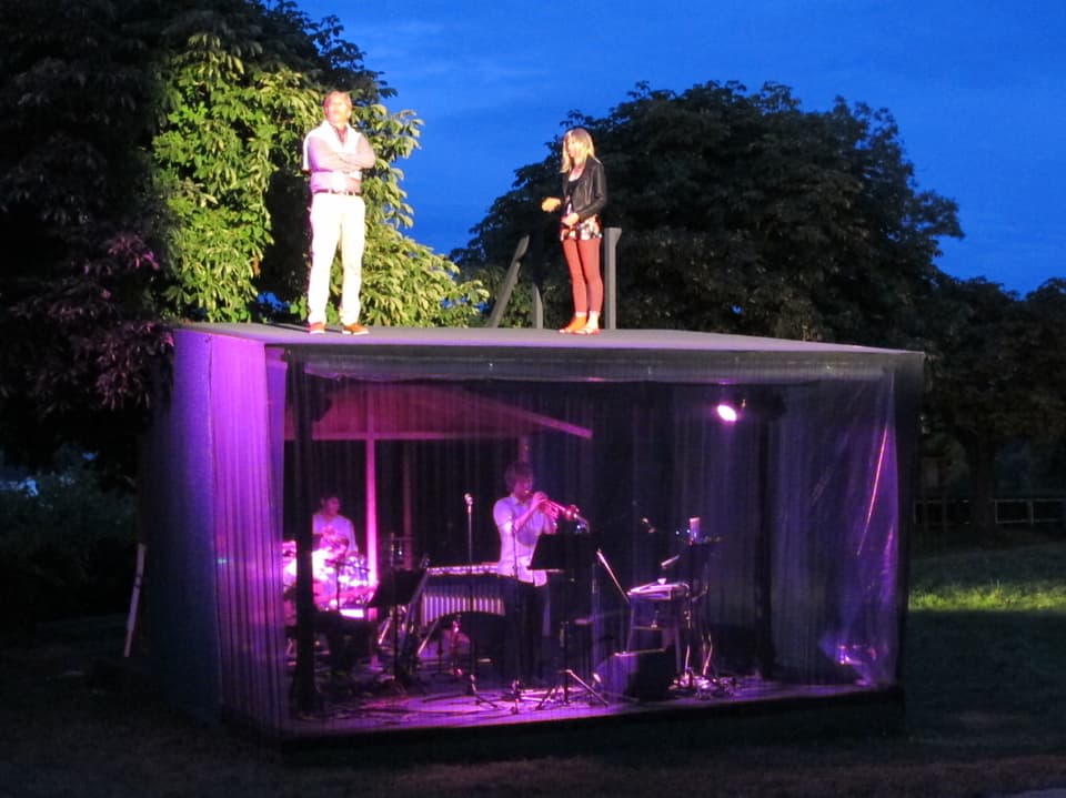 Zwei Schauspieler auf einer Baracke mit Musikern