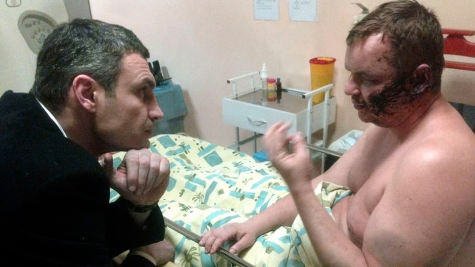 Vitali Klitschko redet am Krankenbett mit dem schwer misshandelten Aktivisten Dmitri Burlatow.