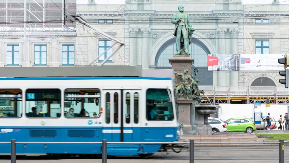 Ein Tram fährt an einer Statue vorbei.