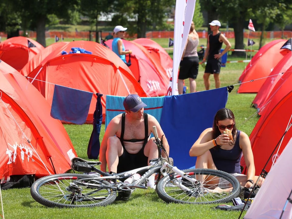 Athleten vor roten Zelten. 