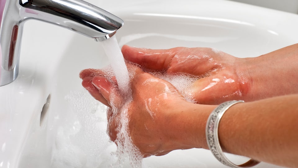 Eine Frau wäscht ihre Hände, am Arm ein solberner Reif.