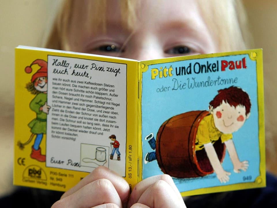 Ein Kind mit blonden Haaren liest ein Pixi-Buch.