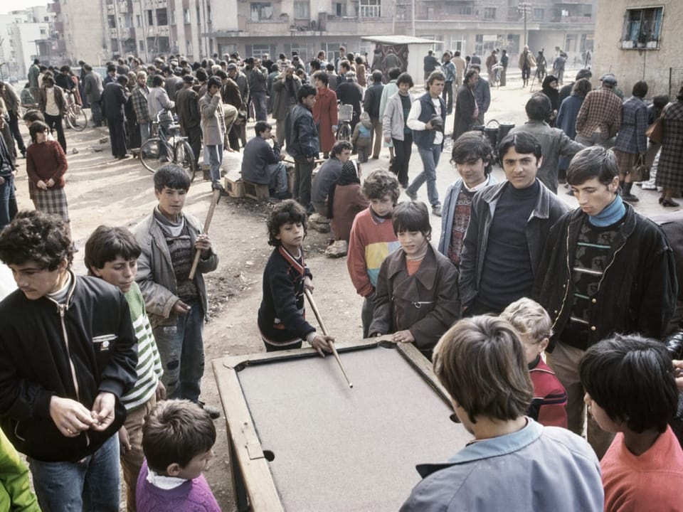 Kinder spielen auf einer staubigen Strasse Billard.