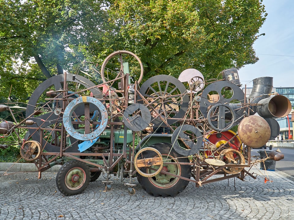 Ein mit Rädern überfülltes Gefährt von Jean Tinguely auf einer Strasse in Basel. 