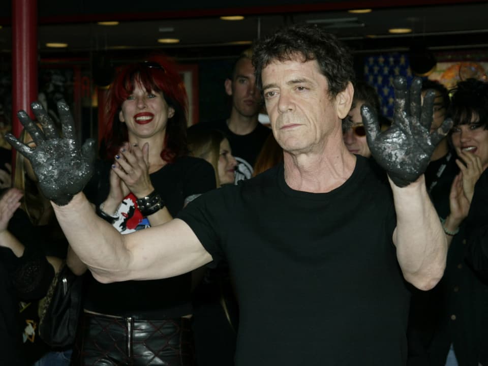 Lou Reed zeigt seine mit Zement überzogenen Hände.