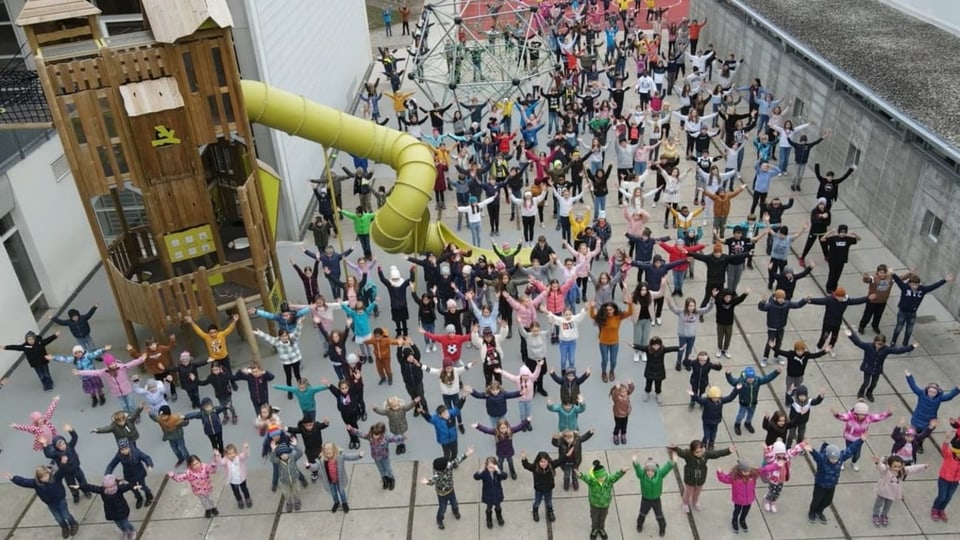 Hunderte Kinder tanzen auf einem Pausenplatz bei der Aktion Say Hi 