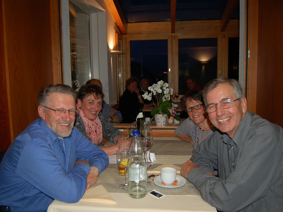 Fröhliche Männer und Frauen sitzen an einem Tisch in einem Restaurant.