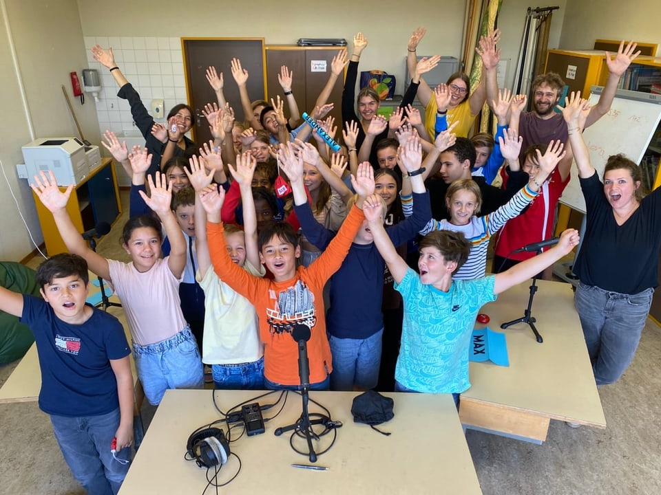 Das Abschlussfoto der 6. Klasse aus Schliern, bei dem alle Kinder und Erwachsenen die Arme in die Luft strecken.