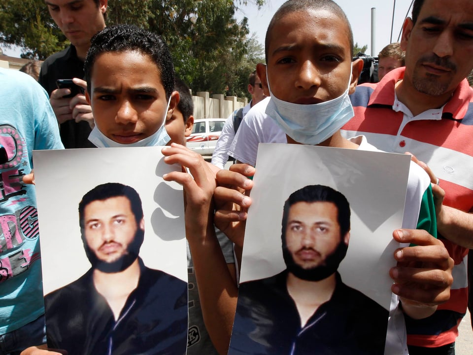 Zwei junge Männer halten Bilder von Saif al-Arab.