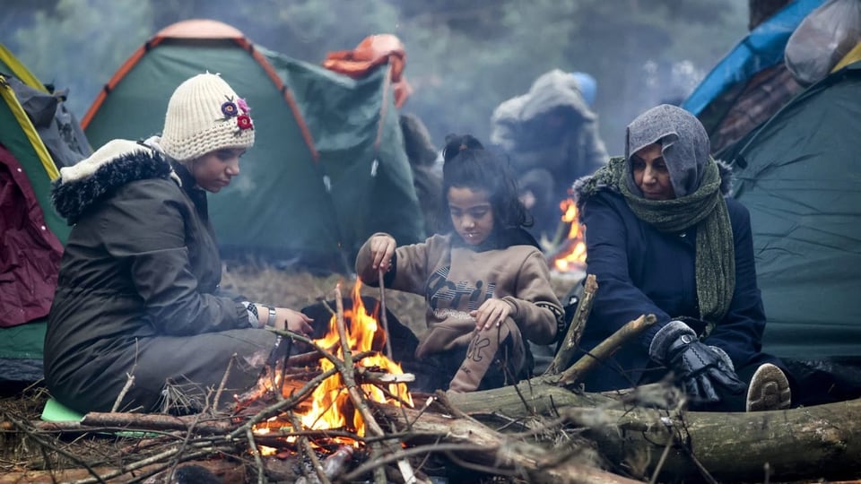 Eine Flüchtlingsfamilie wärmt sich an einem Feuer auf