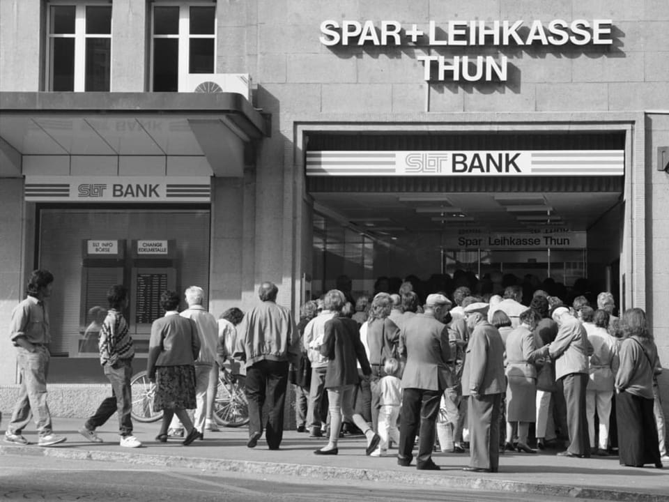schwarzweiss-Foto Menschenmenge vor einer Bank