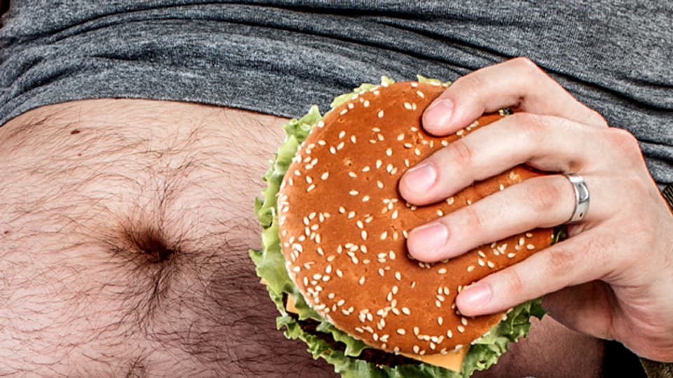 Ein Bauchnabel und eine Hand mit einem Hamburger.