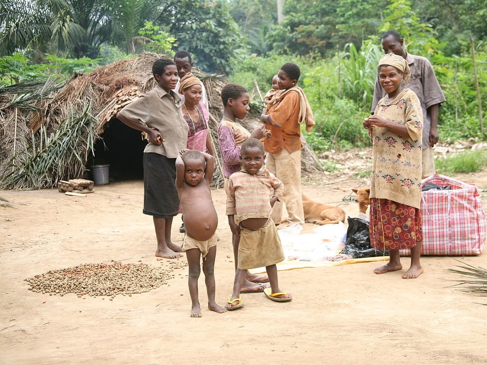 Eine Baka-Familie vor ihrer Laubhütte - die Kinder mit aufgeblähten Bäuchen.