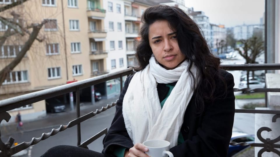 Junge Frau sitzt mit Kaffeetasse auf Balkon
