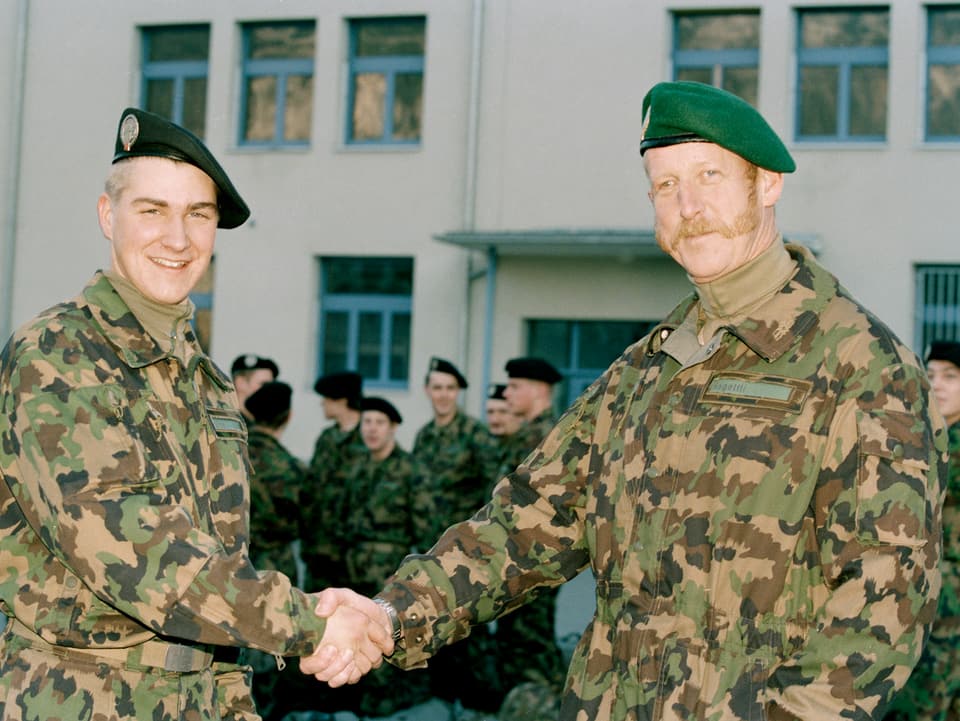 Zwei Männer in Militäruniform geben sich die Hand. 