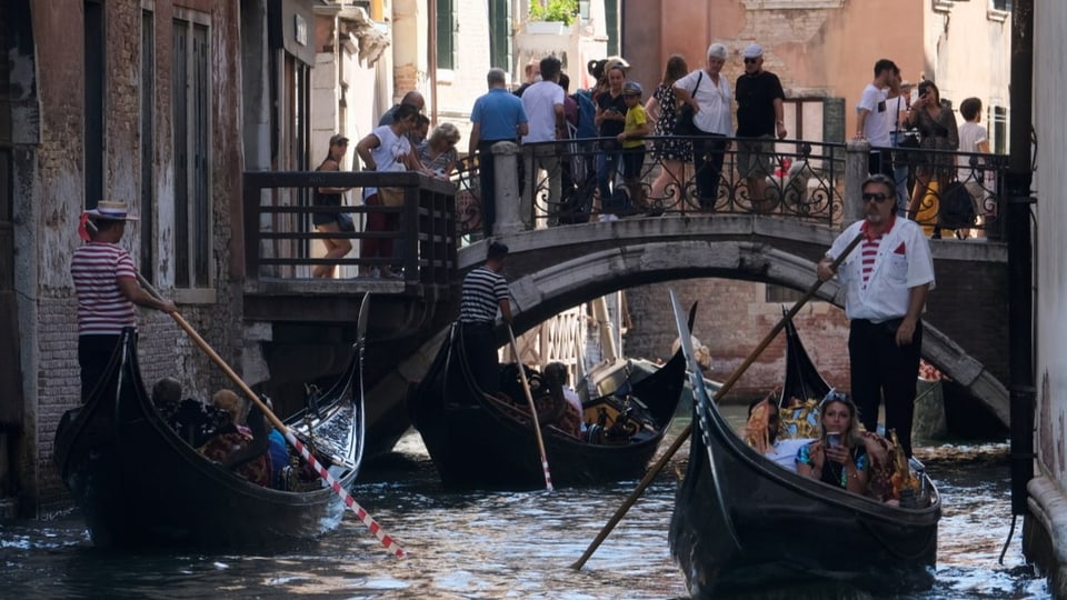 Brücke in Venedig voller Leute, darunter drie Gondeln, ebenfalls mit Kundschaft