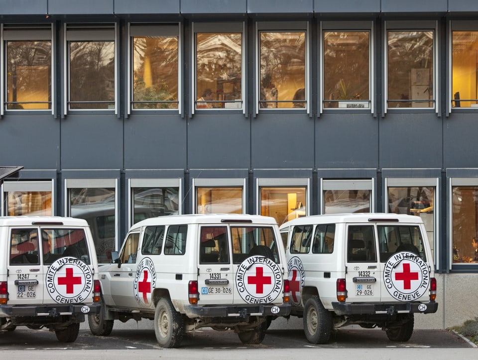 Geländewagen stehen parkiert vor einem Bürogebäude des IKRK in Genf.