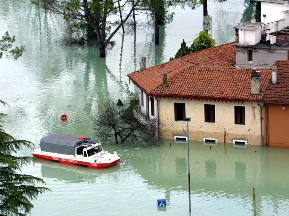 Ein Schwimmfahrzeug plügt sich durch das Hochwasser in einem italiensichen Ort