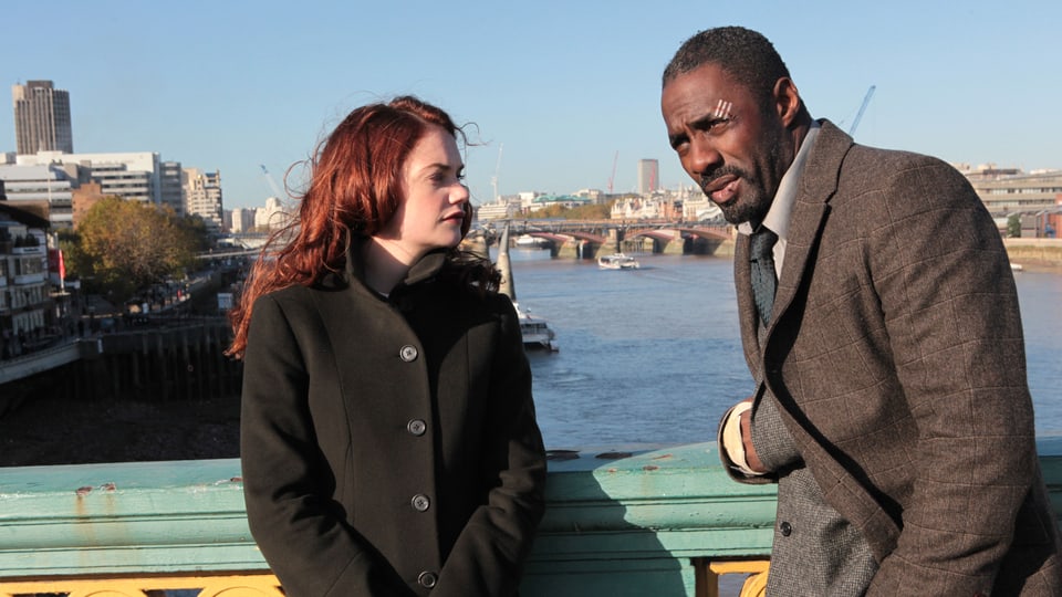 Der Schauspieler Idris Elba und seine Schauspielkollegin Ruth Wilson lehnen an einem Brückengeländer