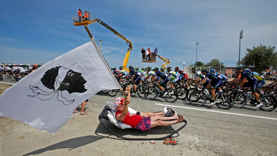 A fan cheers the pack of riders as it cycles on its way during the 213 km first stage of the centenary Tour de France cycling race from Porto-Vecchio to Bastia, on the French Mediterranean island of Corsica June 29, 2013.