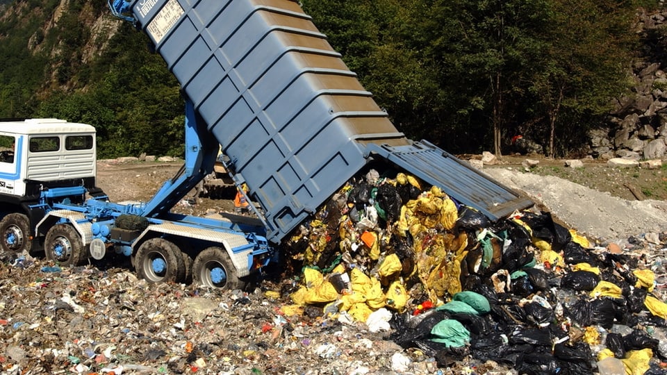 Lastwägen lädt Müll in Deponie ab. 