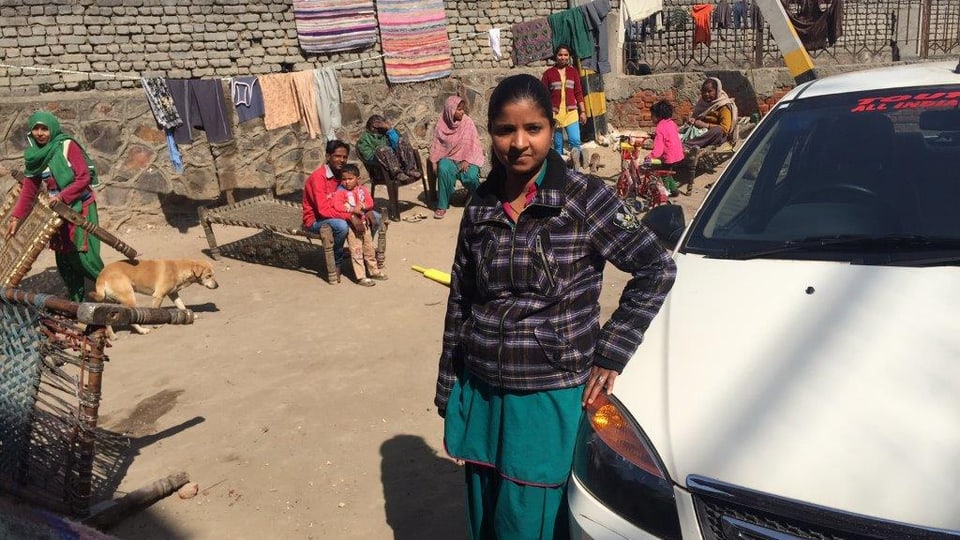 Savita, angelehnt an ihr Taxi, hinter ihr Einwohner von Delhi. 