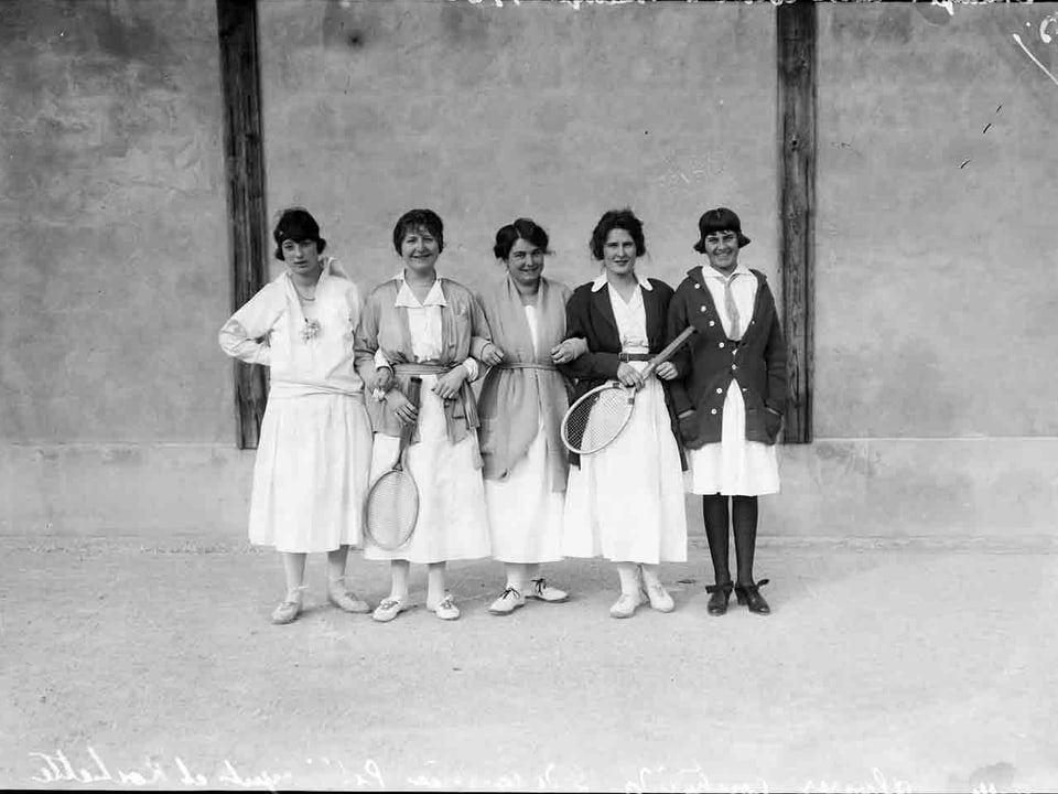 Fünf Frauen untergehakt mit Tennisschläger in der Hand.