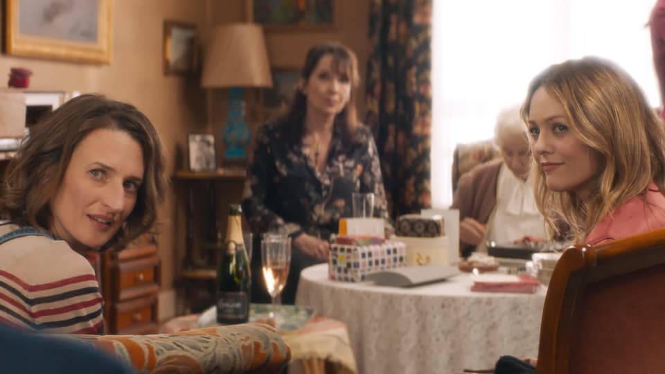 Tisch in einem Wohnzimmer, an dem vier Frauen unterschiedlichen Alters sitzen