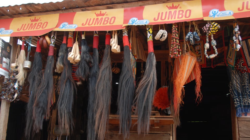 Voodoo-Zubehör – Haare, Ketten, Armringe und kleine Trommeln – an einem Marktstand.