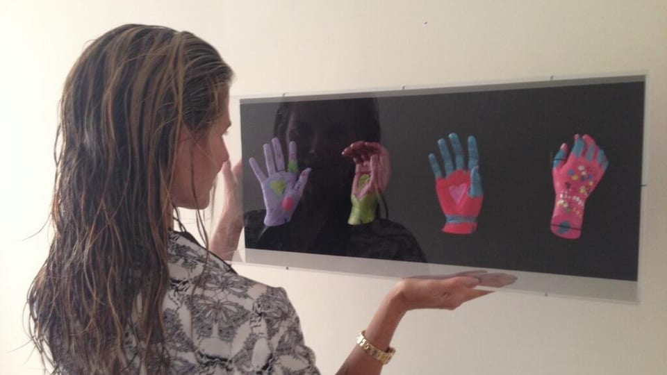 Heidi Klum mit einem Bild, auf dem vier bemalte Hände zu sehen sind.