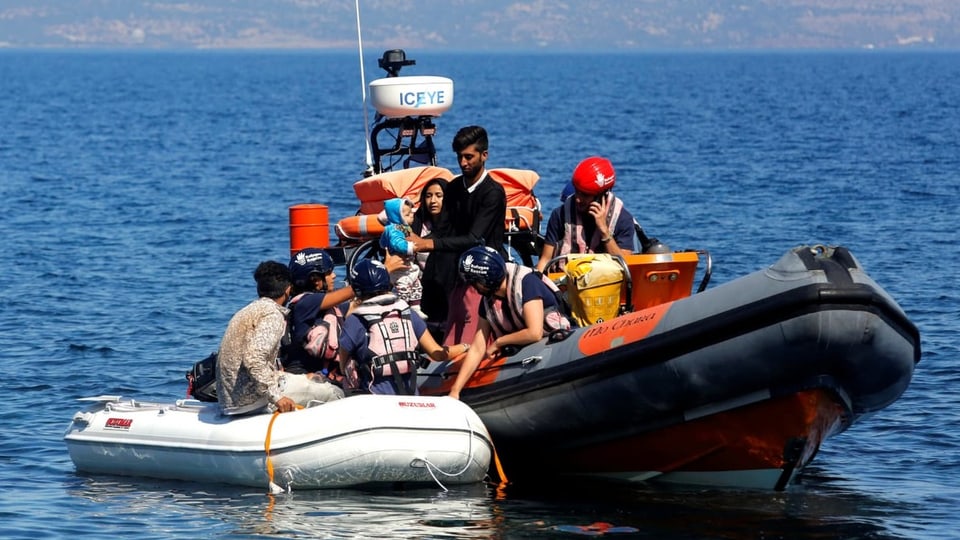 Flüchtlinge sind auf einem Boot. Sie werden von der Küstenwache abgeholt.