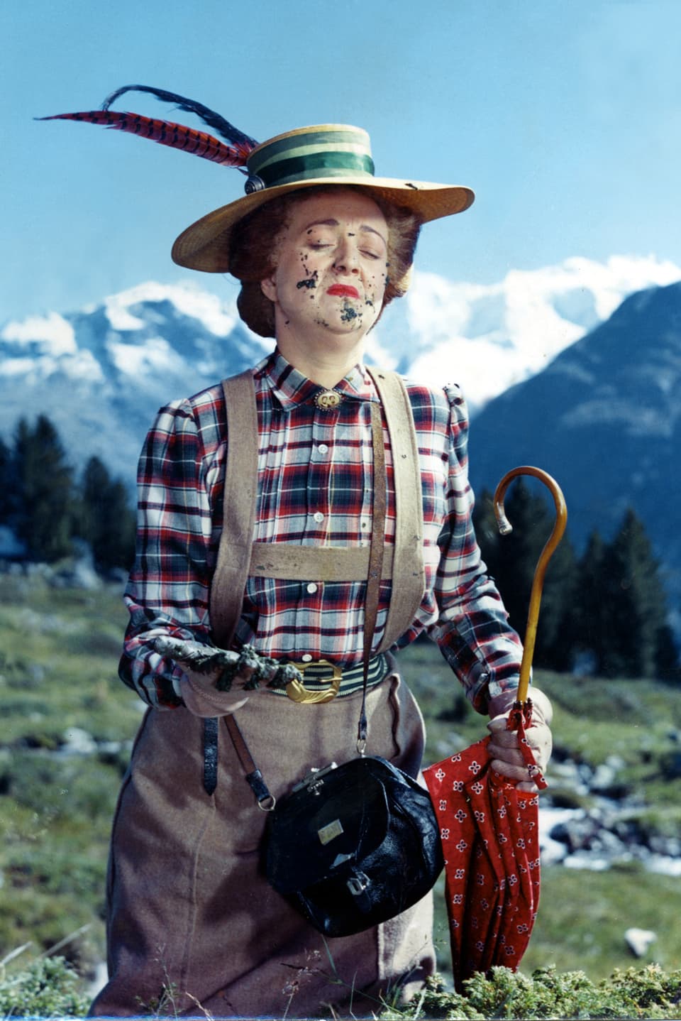 Fräulein Rottenmeier in einer Kuhwiese. Angeekelt betrachtet sie einen Kuhfladen, von dem sie gerade im Gesicht angesprizt wurde.