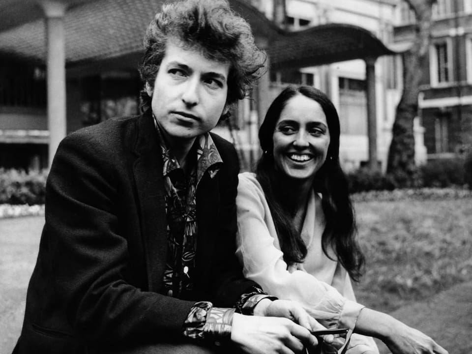 Junger Mann und junge Frau sitzen vor einem Haus