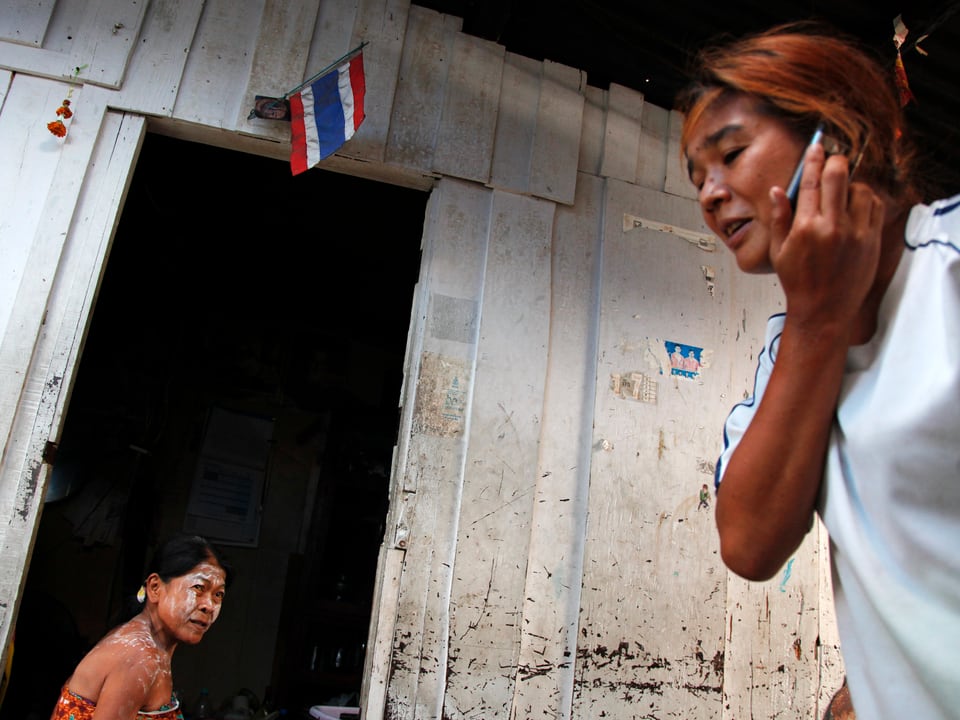Eine Frau telefoniert im Slum von Bangkok