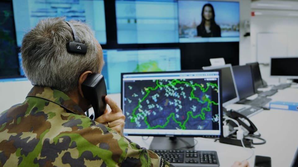 Man sieht einen Mann in Militärkleidung vor einem PC, der die Schweiz auf dem Bildschirm hat.