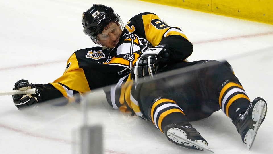 Sidney Crosby liegt mit schmerzverzerrtem Gesicht auf dem Eis.