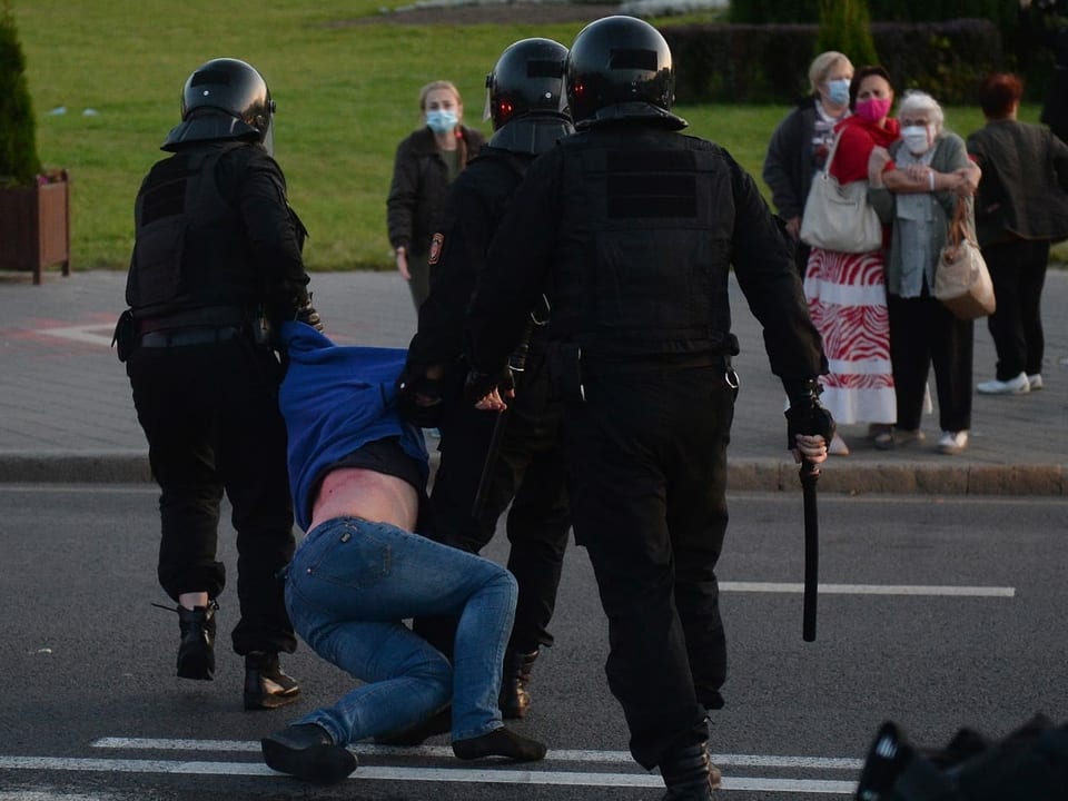 Polizisten schleifen einen Demonstranten rücksichtslos weg, er hat Blessuren am Bauch.