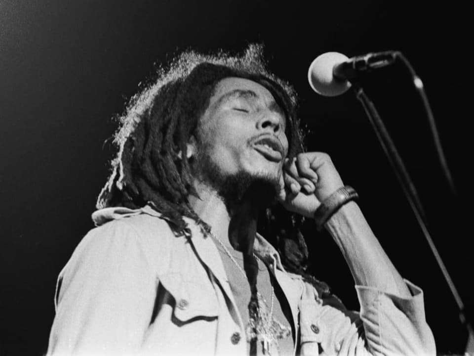 Bob Marley steht auf der Bühne und singt in ein Mikrofon