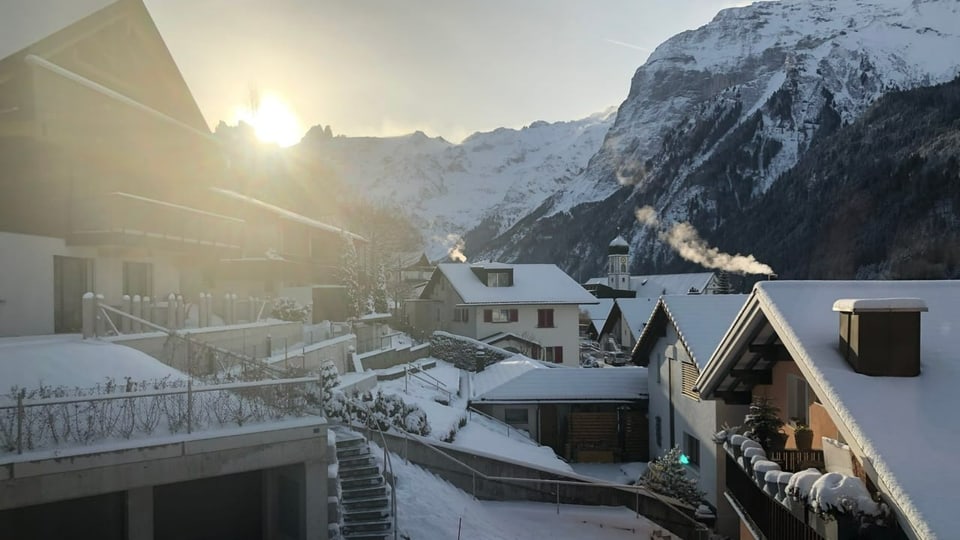 Blick auf verschneite Ferienhäuser in Engelberg bei Sonnenaufgang.