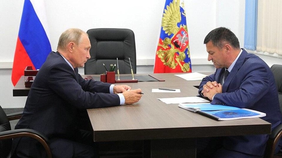 Wladimir Putin und Andrei Tarasenko sitzen sich an einem Tisch gegenüber.