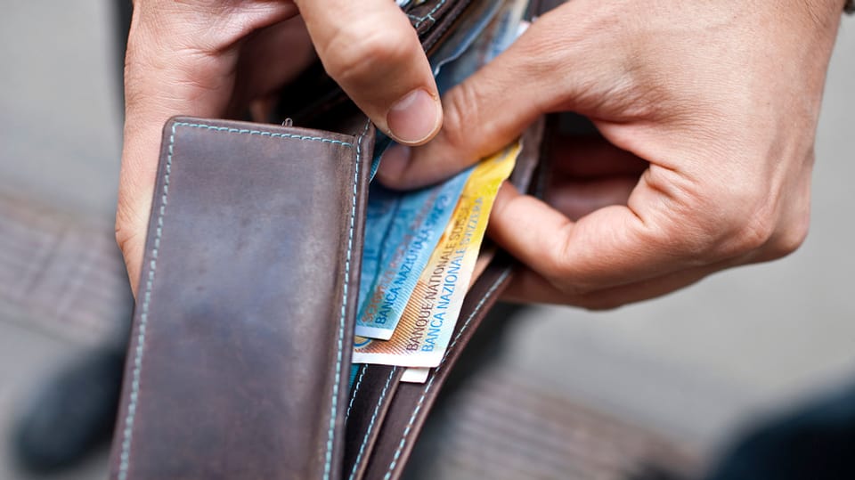 Ein Mann zieht Geld aus seiner Brieftasche.