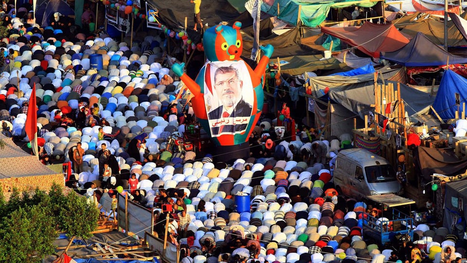 Betende Muslime in Kairo. In der Bildmitte ein Transparant mit Mursi-Konterfei.