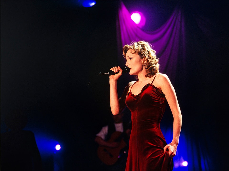 Patricia Kaas steht in einem roten Kleid auf der Bühne und singt.