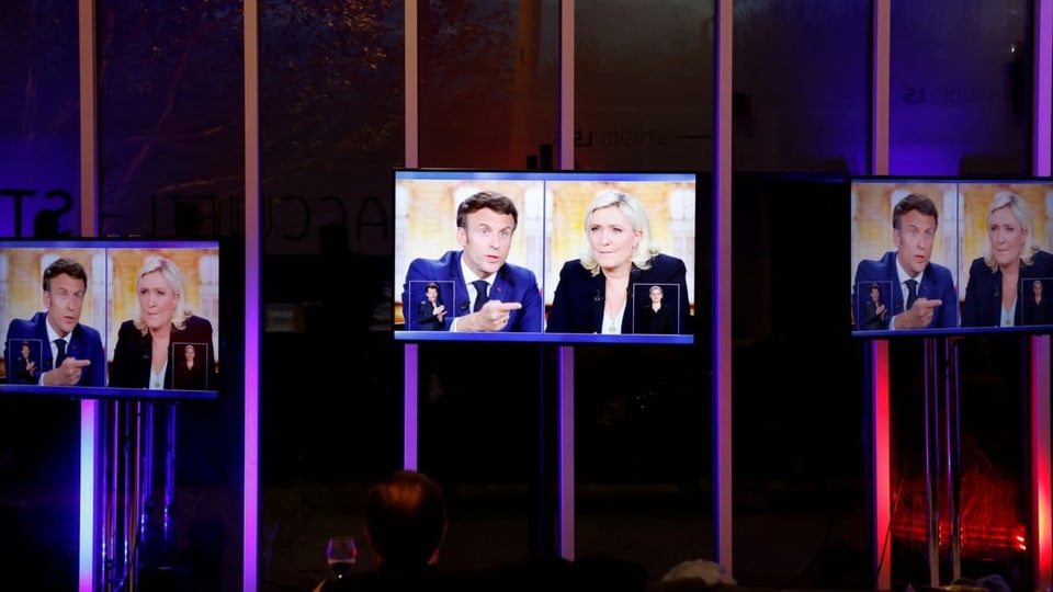 Die Debatte von Macron und Le Pen wird auf drei Bildschirmen gezeigt.
