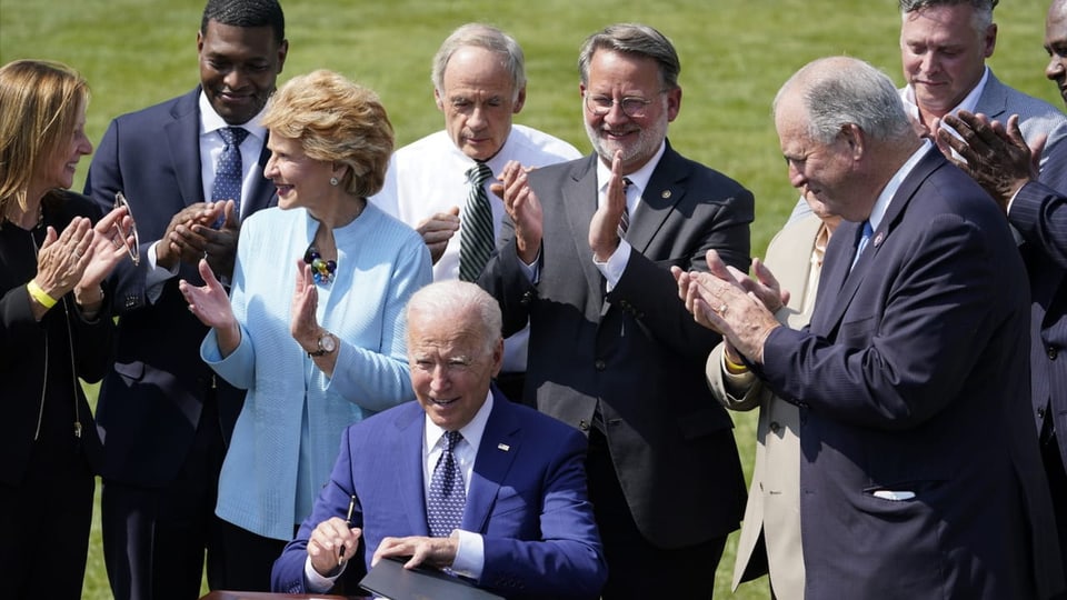 Joe Biden beim Unterschreiben unter freiem Himmel..