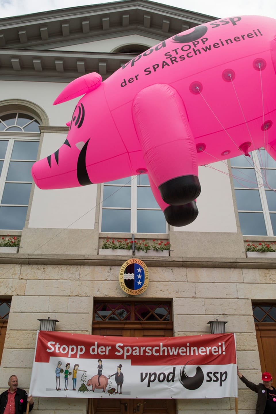 Demonstration Lehrer mit grossem rosa Sparschwein-Ballon
